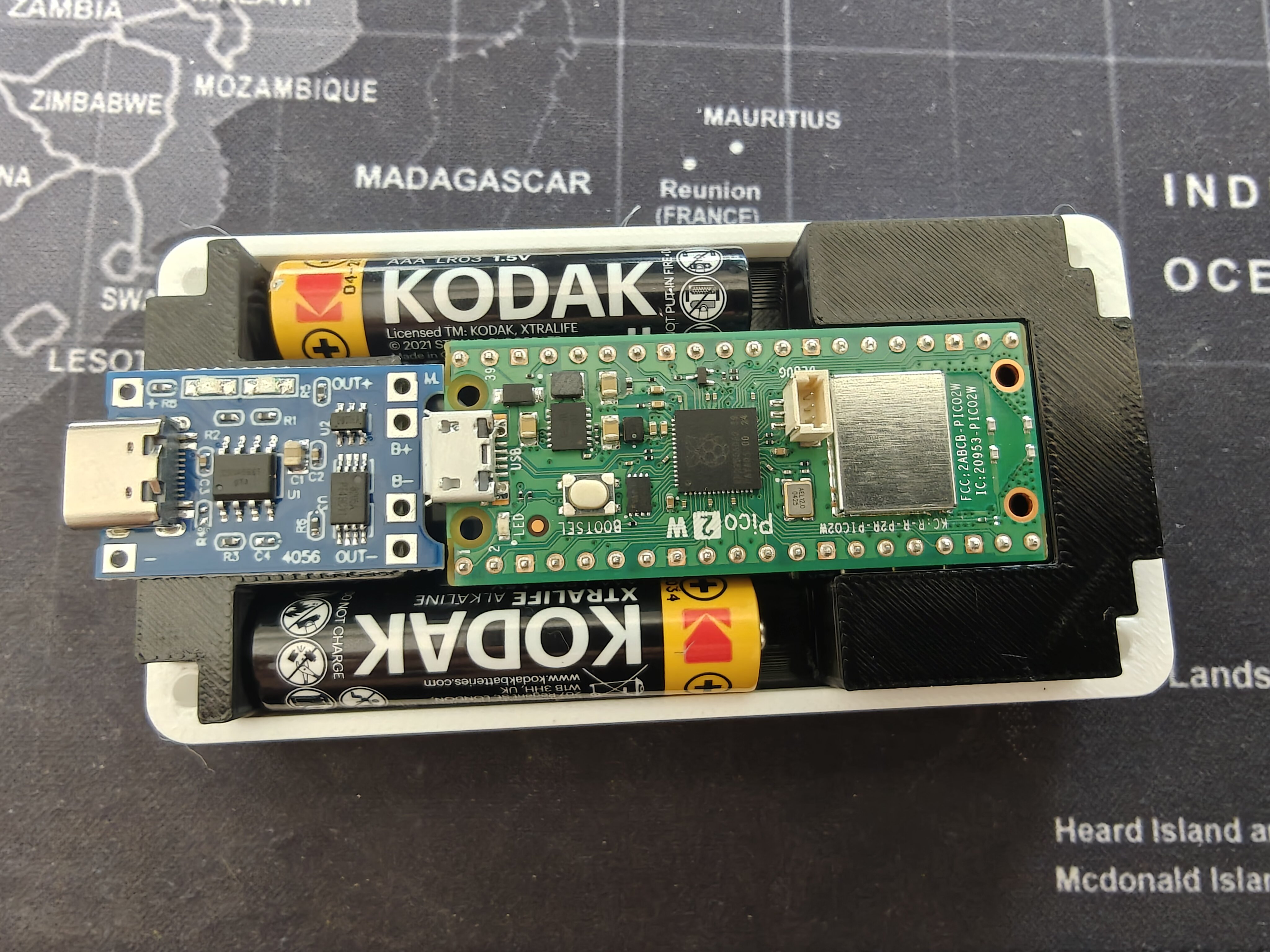 TP4056 charge board placement reference — board sitting at the -X end between batteries