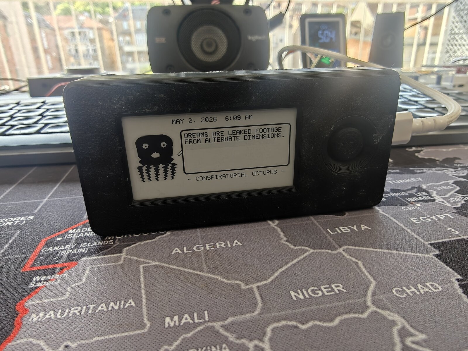 Fully assembled Dilder in black NoSolar case — e-ink display showing Conspiratorial Octopus, battery powered