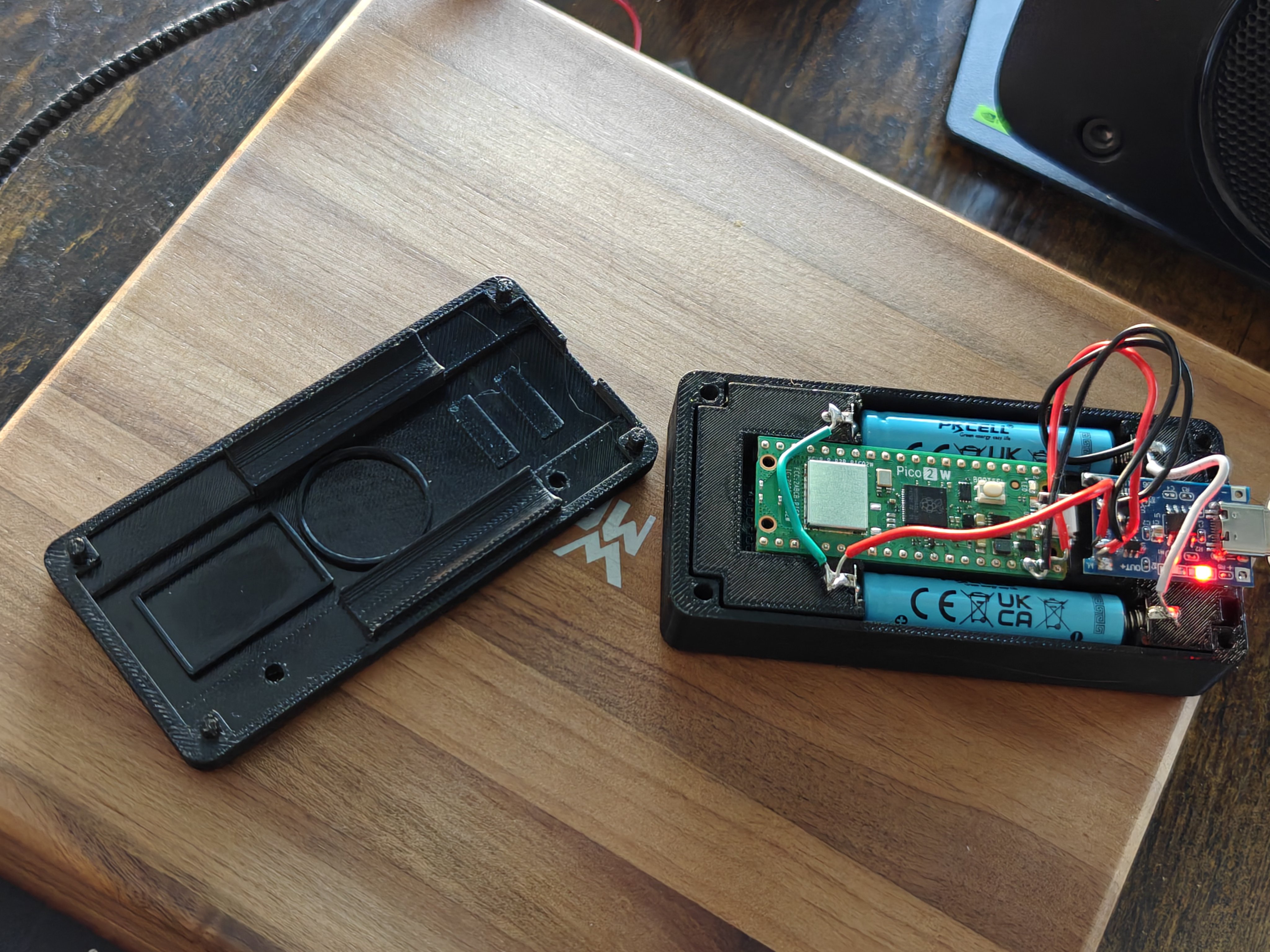NoSolar case opened — base plate without solar cutout next to assembled unit with Pico W, 10440 battery, and TP4056 charging via USB