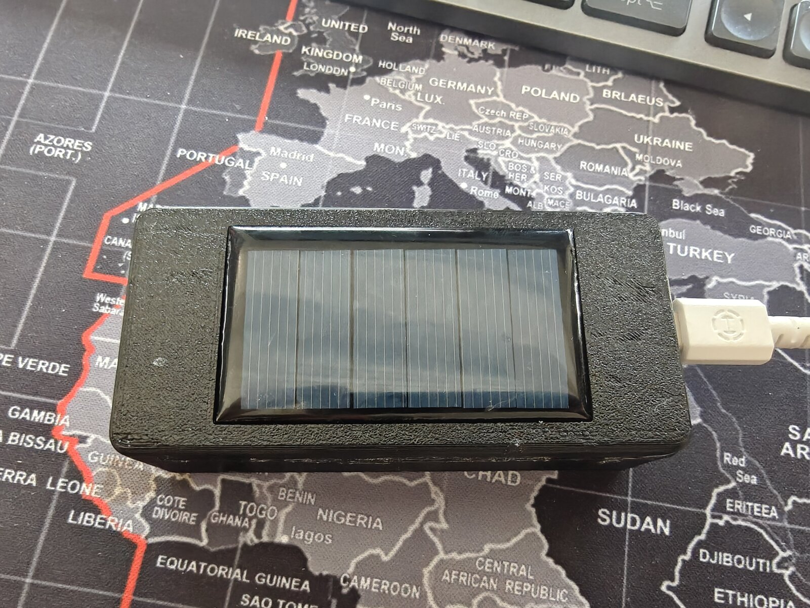 Dilder solar variant — back view showing AK 62x36mm solar panel through the base plate cutout with USB cable