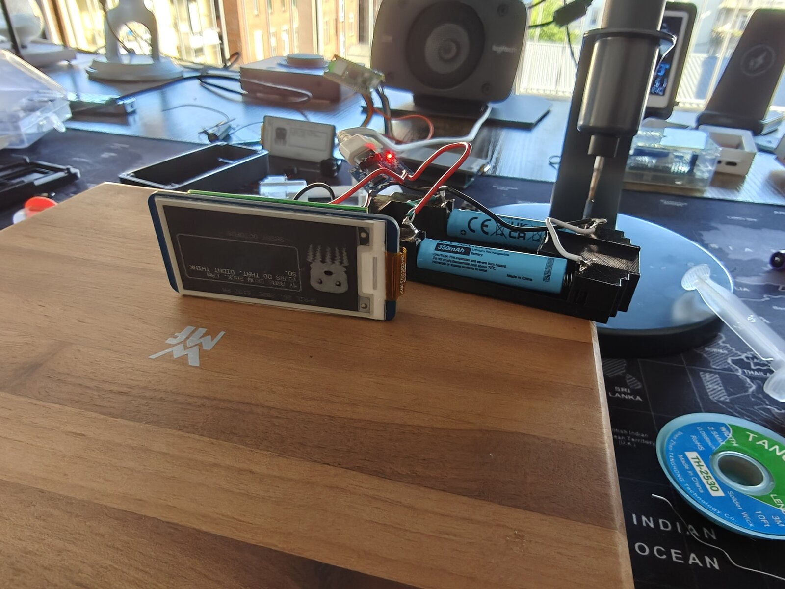Dilder bare board side angle — display running with battery and TP4056 charger visible