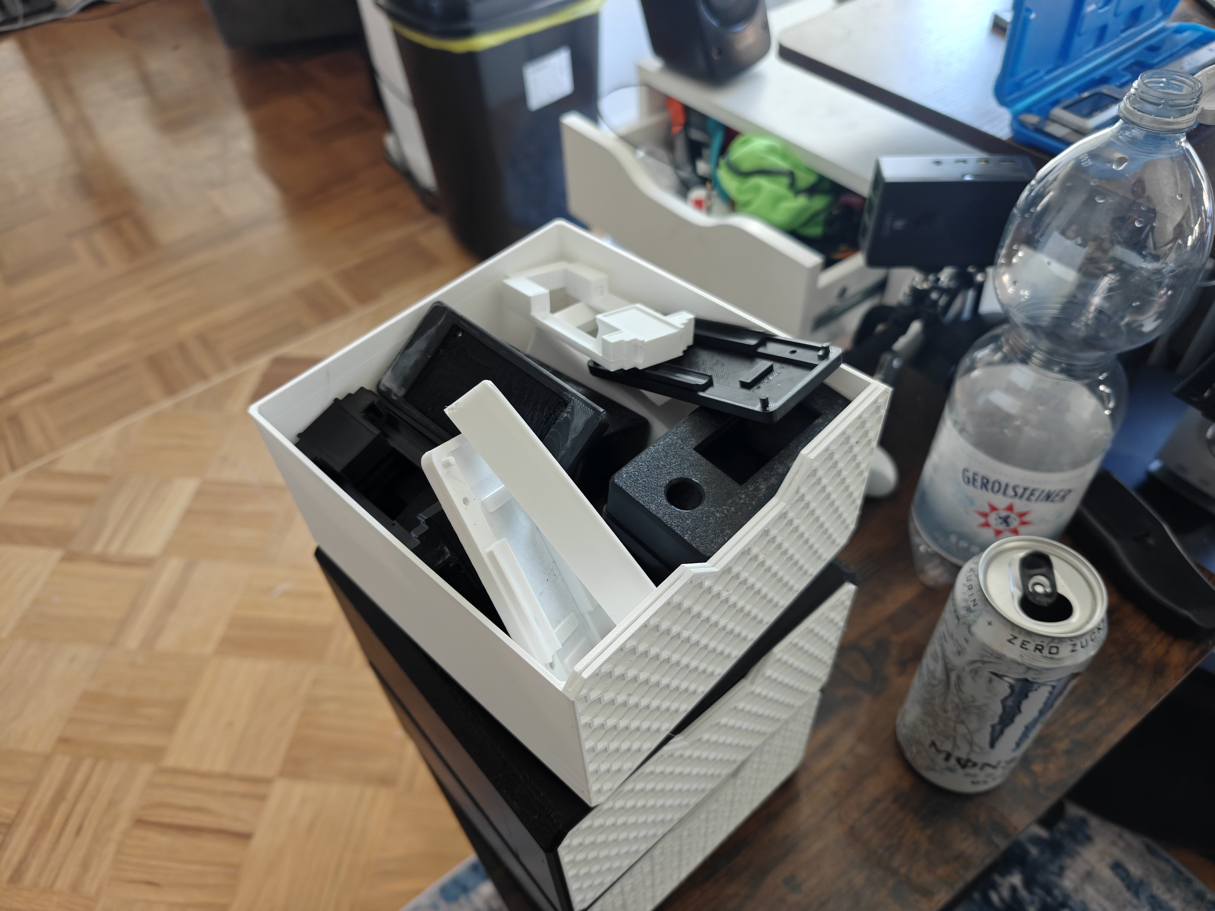3D printer storage drawer with printed Dilder parts — white and black PLA base plates, top covers, cradles, and thumbpieces
