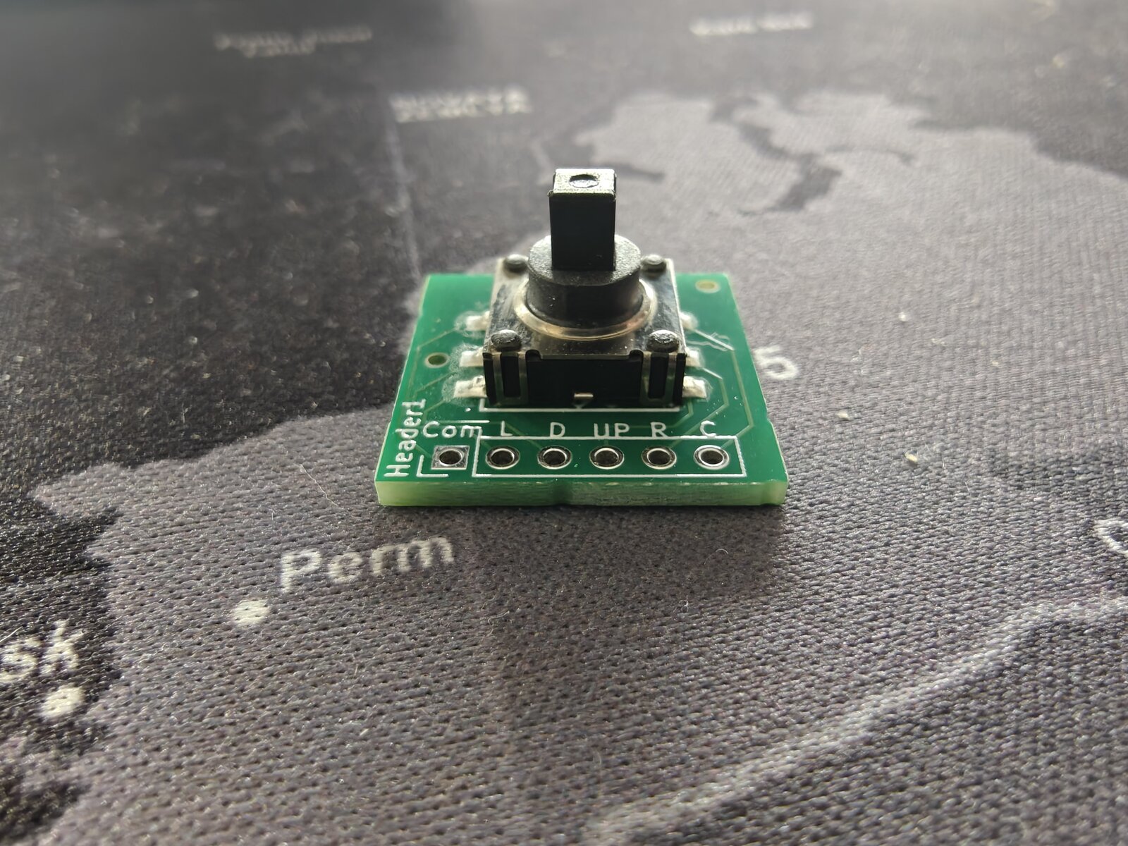 Single joystick breakout board snapped from panel — front angle showing K1-1506SN-01 switch actuator peg and solder pads
