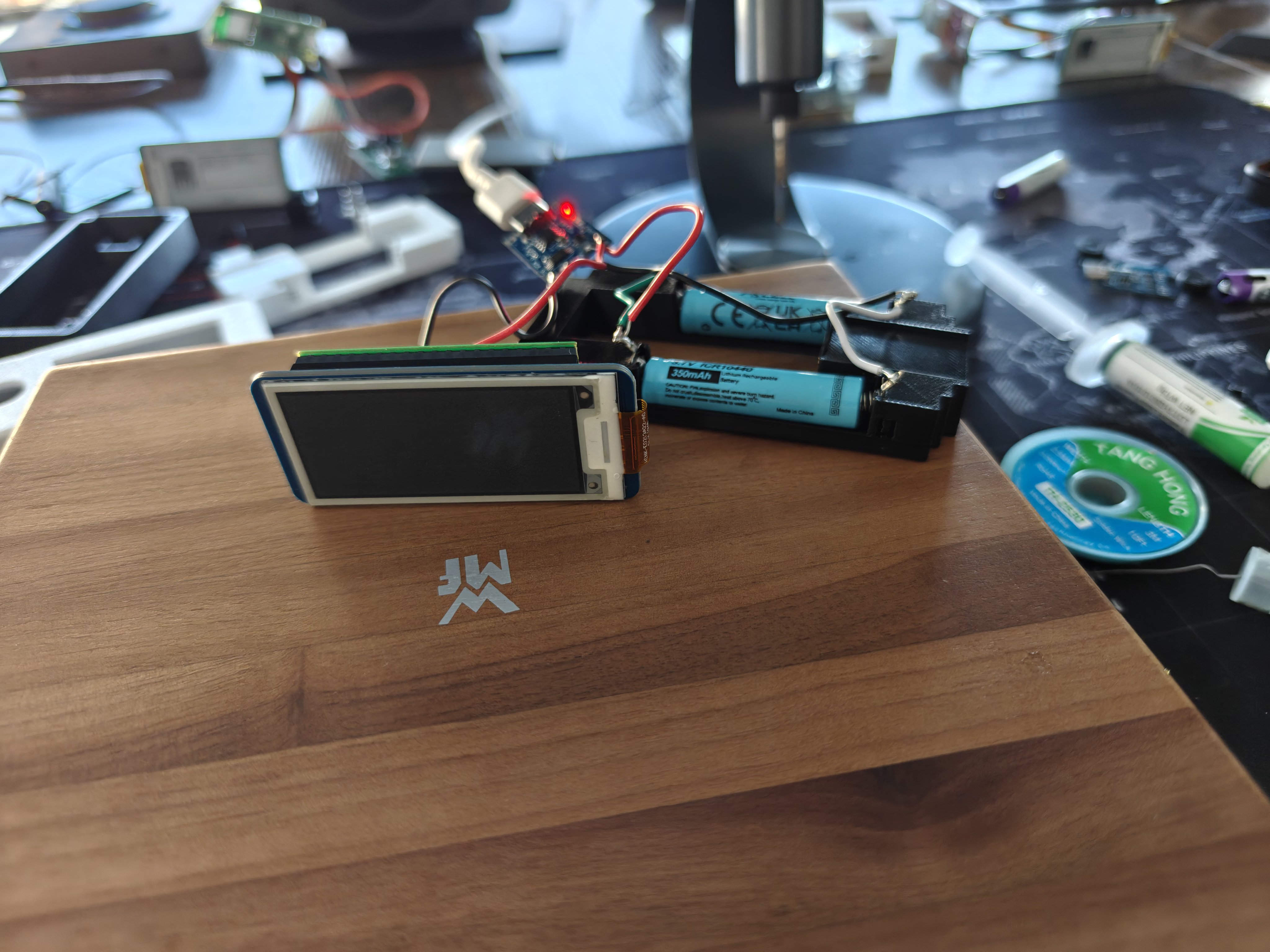 Soldered unit close-up — Pico W, TP4056, and 10440 battery in the AAA cradle with visible solder joints and wire routing